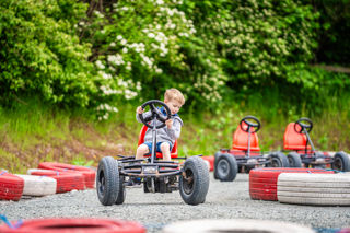 An image of a boy whizzing round the corner of the race track on a pedal go kart at Cantref Adventure Farm.