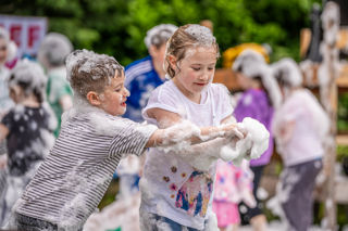 An image of two children trying to gather more foam in their hands.