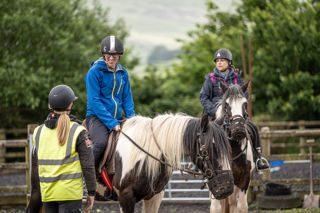 An image of a man smiling on horseback whilst talking to the ride's guide.