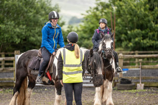 An image of a man smiling on horseback whilst talking to the ride's guide.