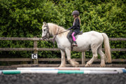 An image of a girl riding a small white horse around Cantref Riding Centre's training area.
