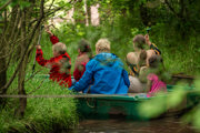 An image of four children and one adult in a green row boat, going round a jungle swamp course at Cantref Adventure Farm.