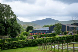 An image of the side of the pig racing track, looking back at the indoor play buildings and Brecon Beacons behind.