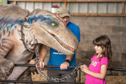 An image of a girl holding a chain attached to Blue the velociraptor whilst they meet.