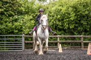 An image of a girl riding a small white horse around Cantref Riding Centre's training area.