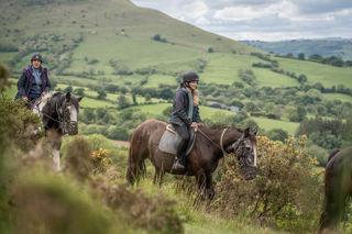 A close up image of a rider on horseback against a backdrop of the stunning Brecon Beacons.