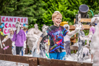 An image of a boy covered in foam with a big grin on his face.
