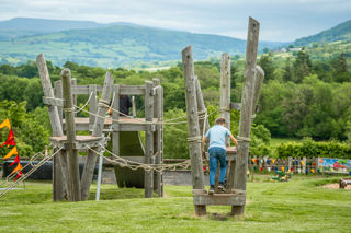 An image of a boy stepping onto a balance rope, with a wonderful panoramic view of the Brecon Beacons.