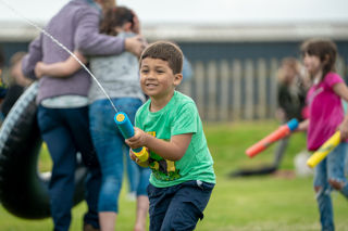 An image of a young boy enjoying firing a water pistol.