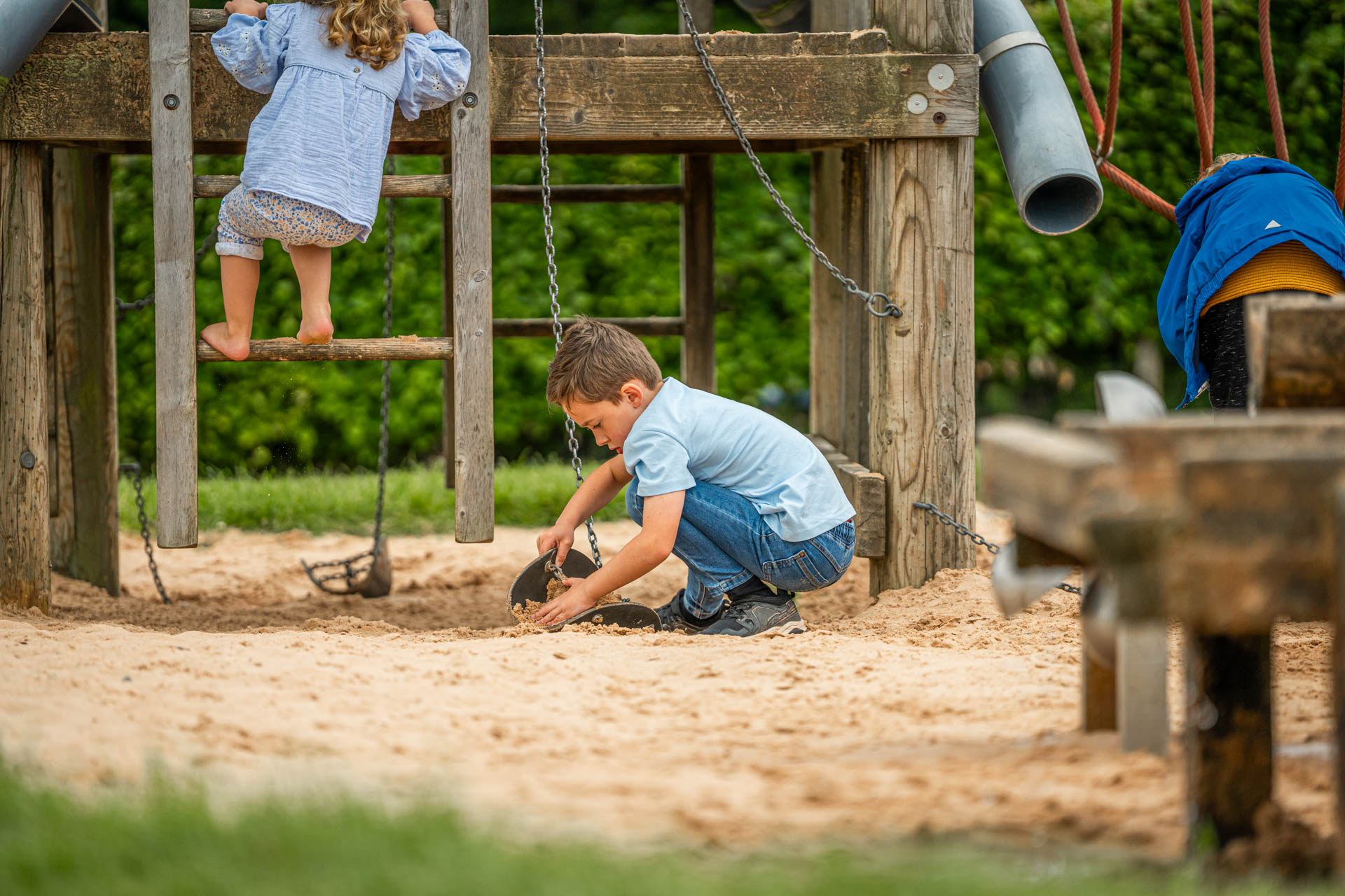 An image of a boy shovelling sand into bucket hoist.