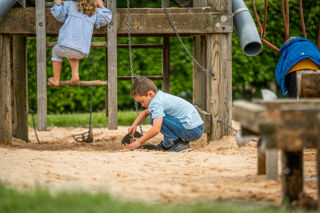 An image of a boy shovelling sand into bucket hoist.