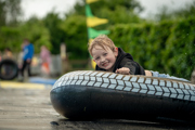 An image of a boy smiling as he zooms down the water slide on an inflatable doughnut.