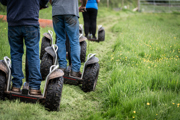 An image of a group of four on Segways going down a mown grass path in single file.