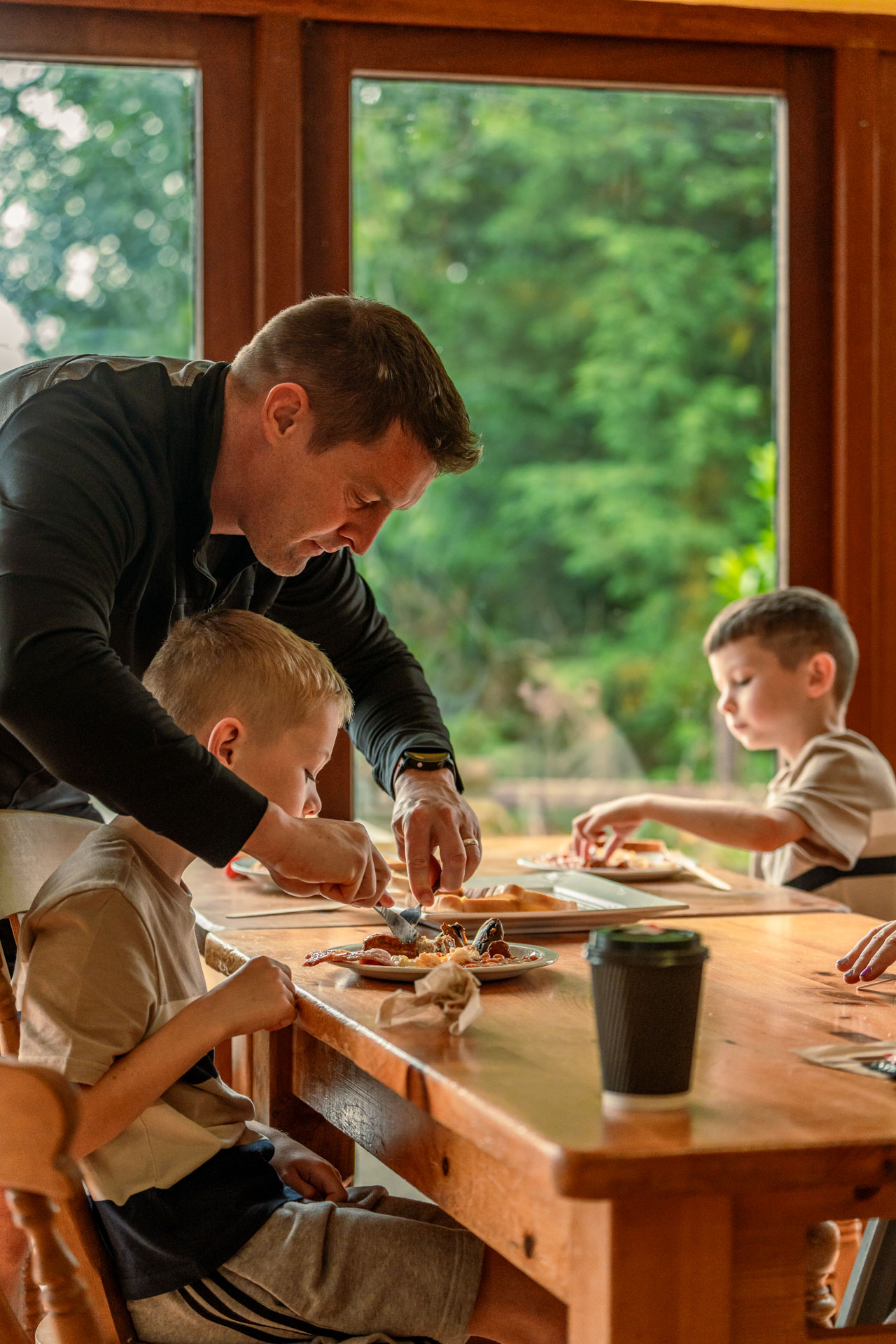 An image of dad helping his son cut up his breakfast.