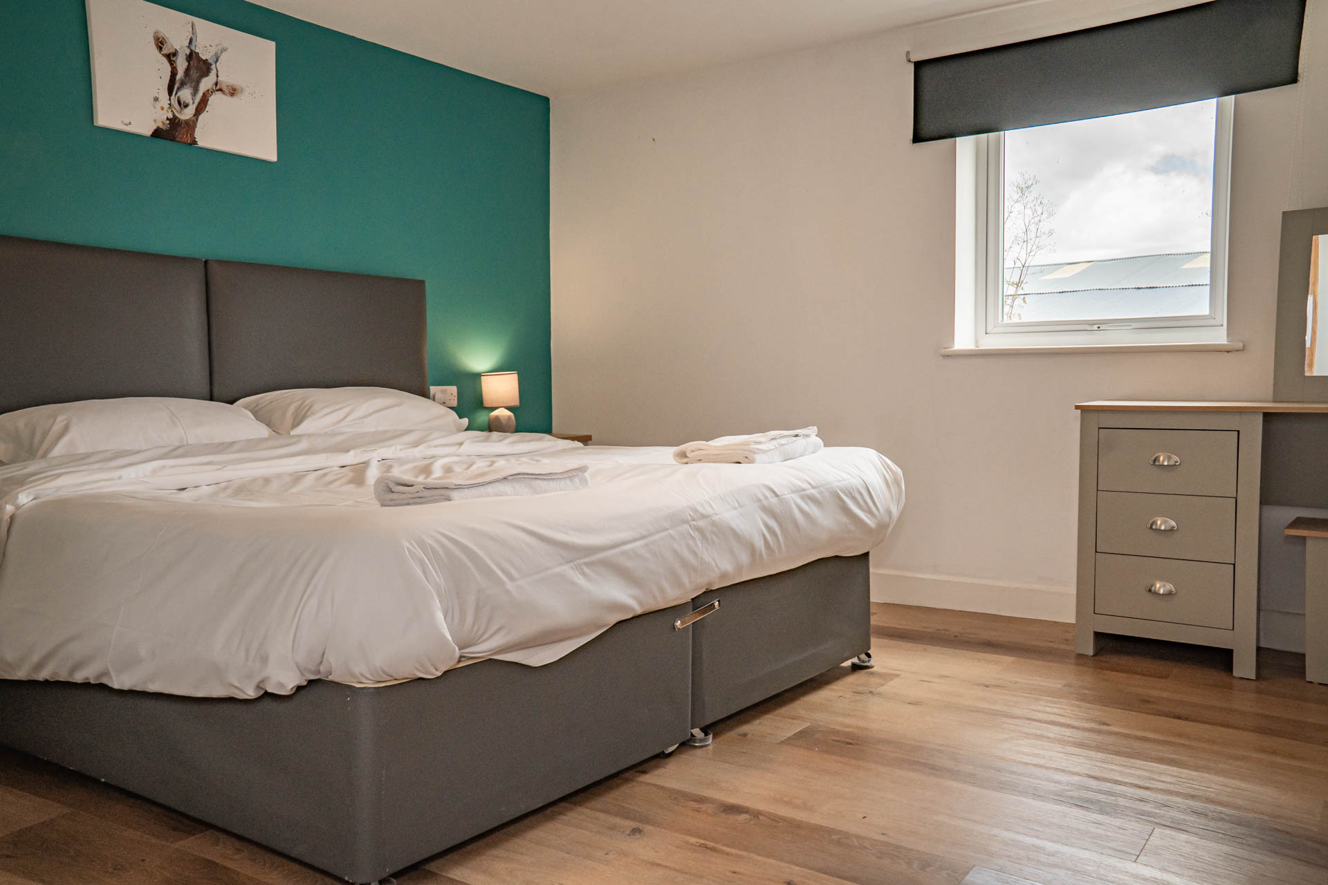 An image of a double bedroom, with white linen and towels and a feature blue wall.