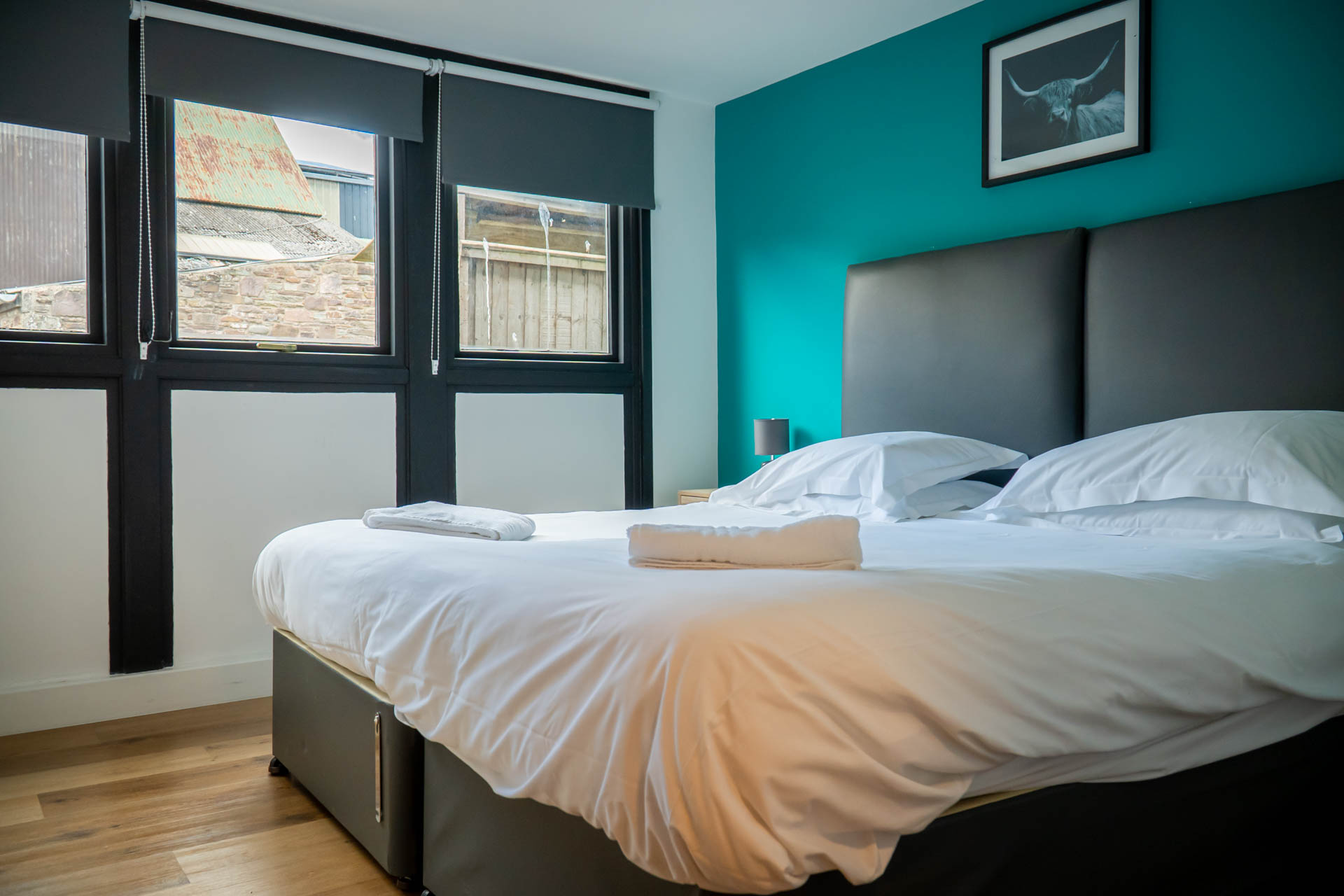 An image of a double bedroom, with white linen and towels and a feature blue wall.