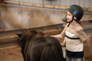 A boy excited to be pampering a pony.