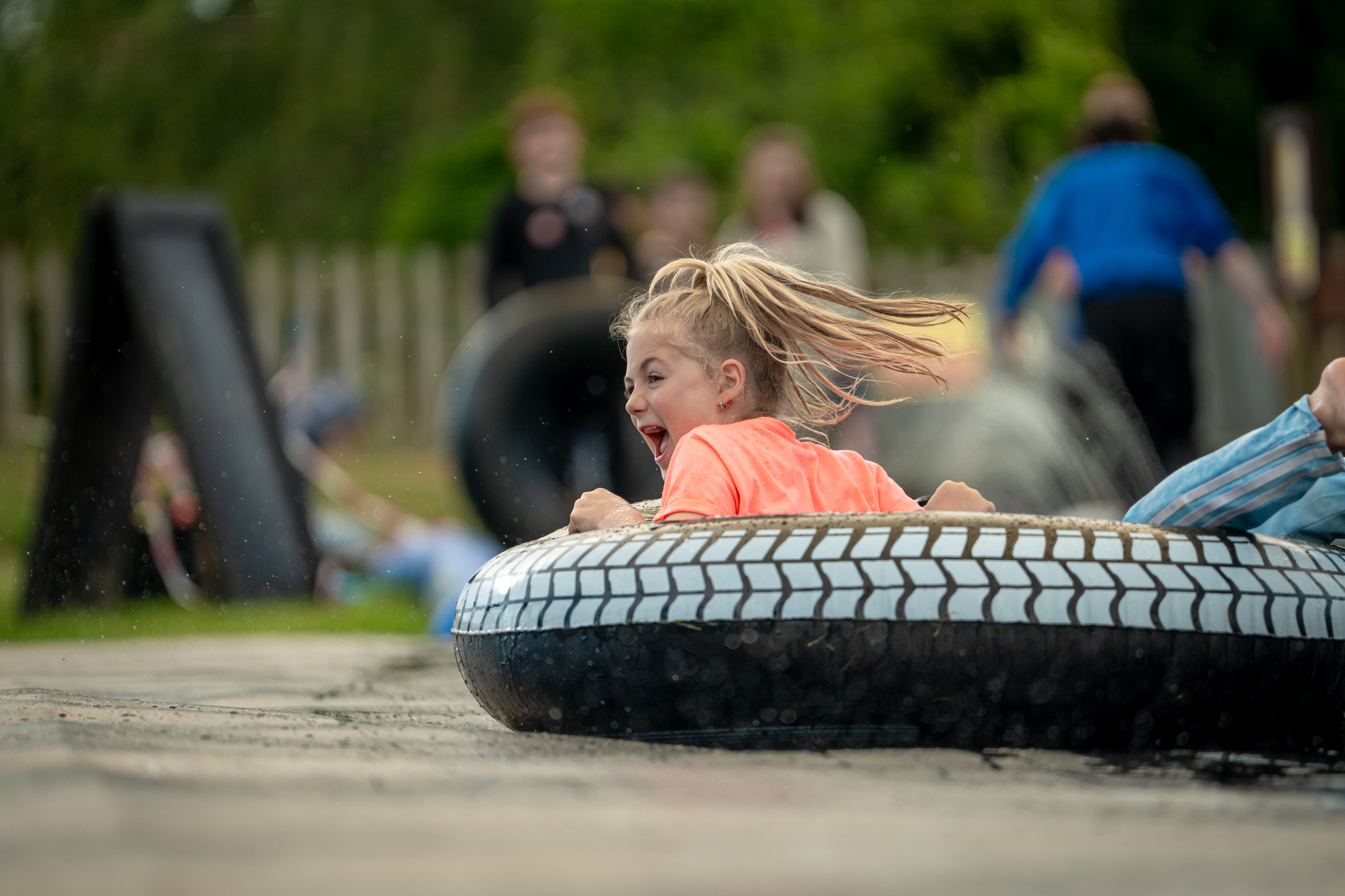 An image of a girl screaming as she spins down the soapy water slide on an inflatable doughnut.