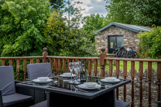 An image of an outdoor seating area on the veranda of The Milking Parlour, the table is set and there's a lovely green view.