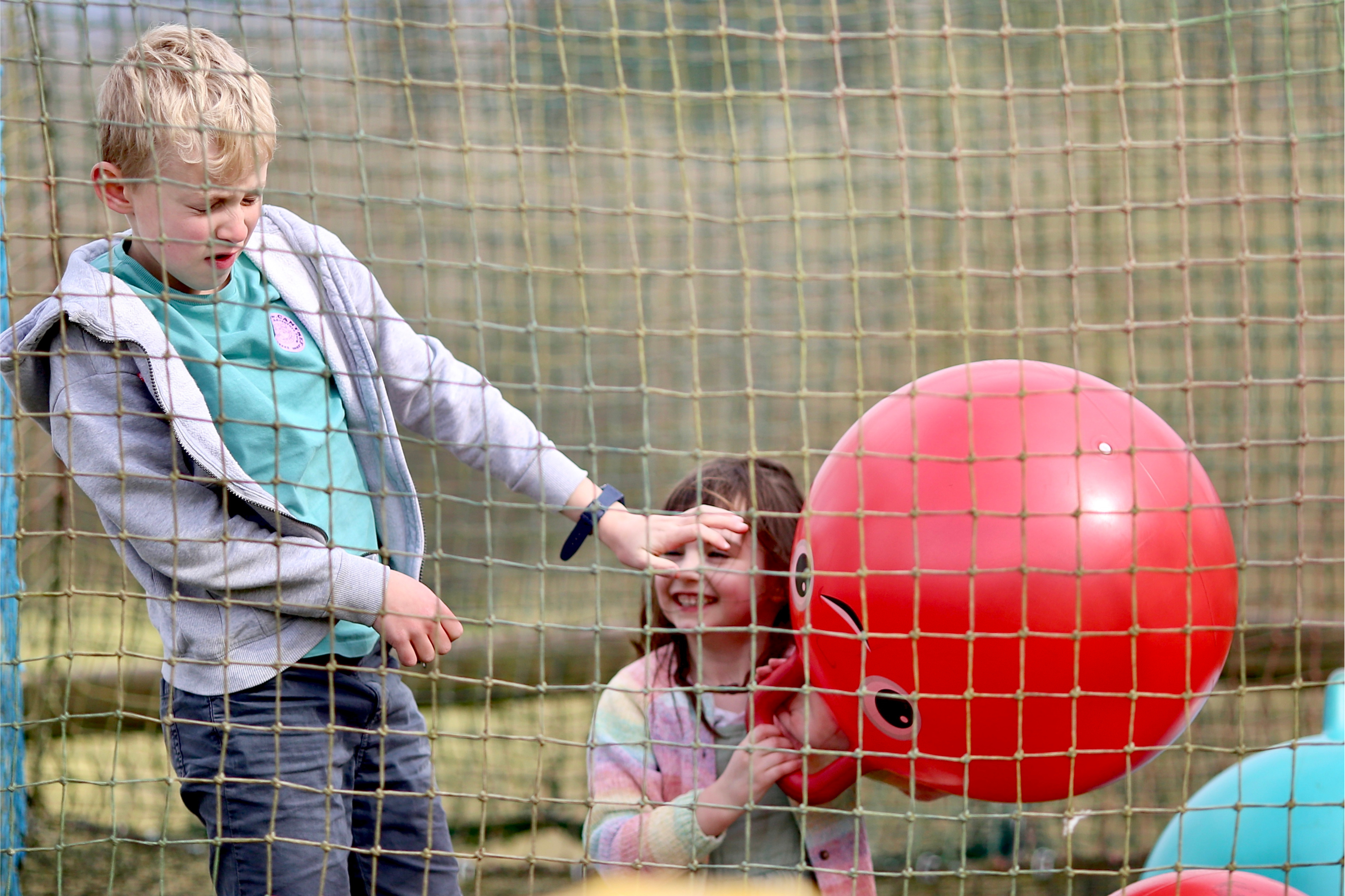 Children playing on a large adventure bounce net with a trampoline at Cantref Adventure Farm