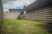 An image of a selection of outdoor games laid out on a small lawned area, next to a hayloft with a tin Barrell Vault roof and exterior wooden cladding.