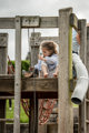 An image of a girl on a wooden platform, playing with a bucket of sand.
