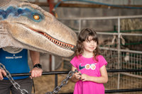 An image of a girl posing to have her photo taken with Blue the velociraptor.