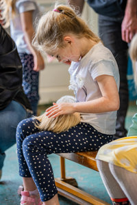 An image of a girl gently stroking a guinea pig rested on her lap in the petting barn at Cantref Adventure Farm.